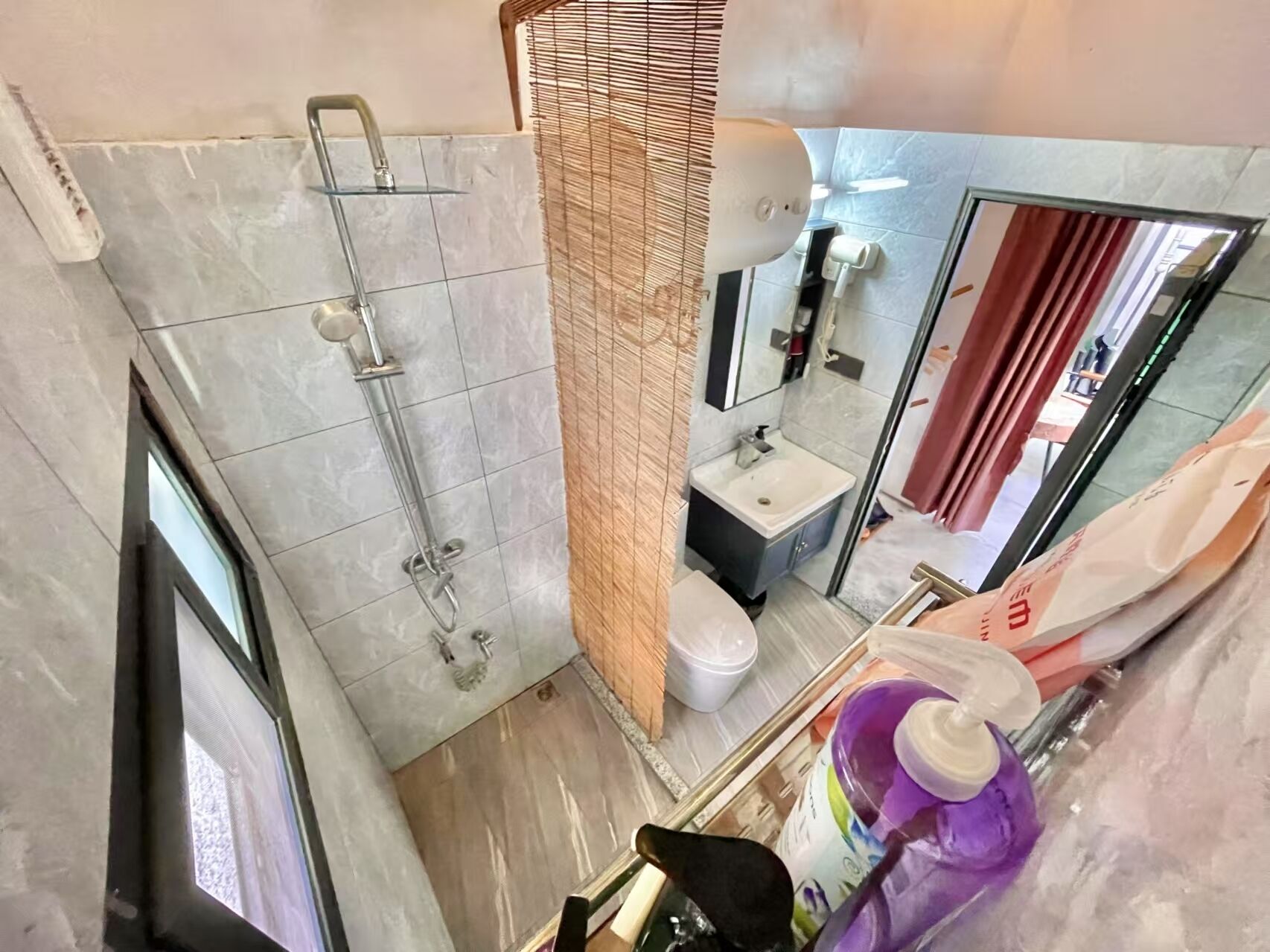 A bathroom with a shower, toilet, sink, and mirror.