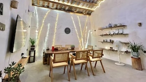 A dining area with a wooden table and chairs, a ceiling with a decorative light fixture, and shelves with decorative items. - Serenity Courtyard Hotel (Shantou)