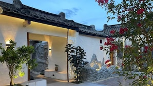 A traditional-style building with a courtyard, stone wall, and potted plants. - Serenity Courtyard Hotel (Shantou)