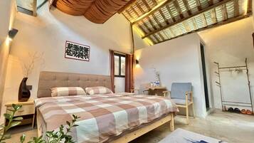 Un dormitorio con una cama grande, un cabecero de madera, una mesita con un jarrón y un zapatero.
