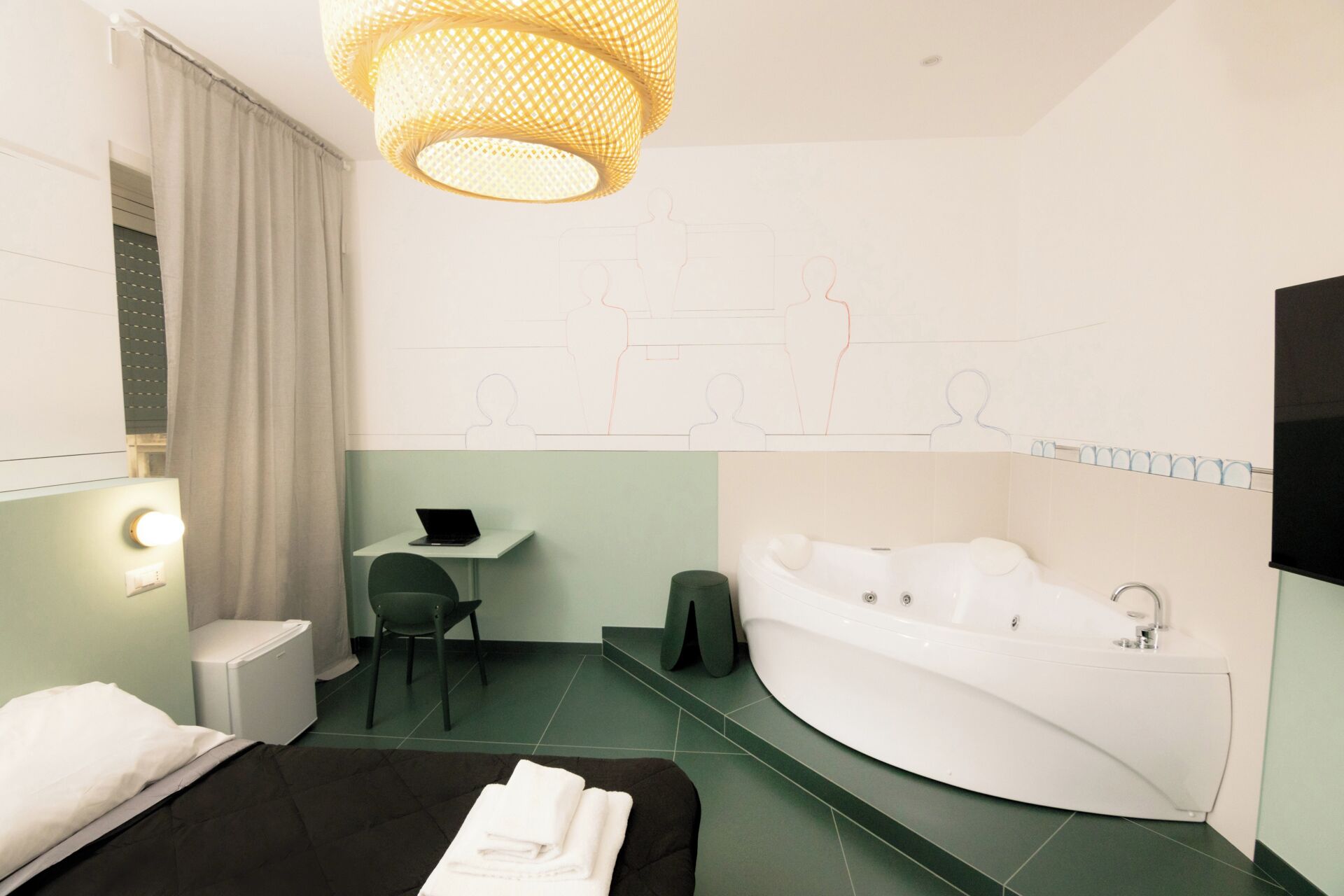 A modern hotel room with a bed, a desk, a laptop, a chair, a sofa, a bathtub, and a large window.