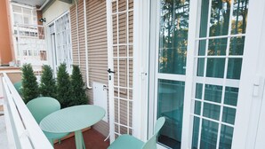 A balcony with a round table and two chairs, a sliding glass door, and a small tree. - O Effe Games Vatican (Rome)