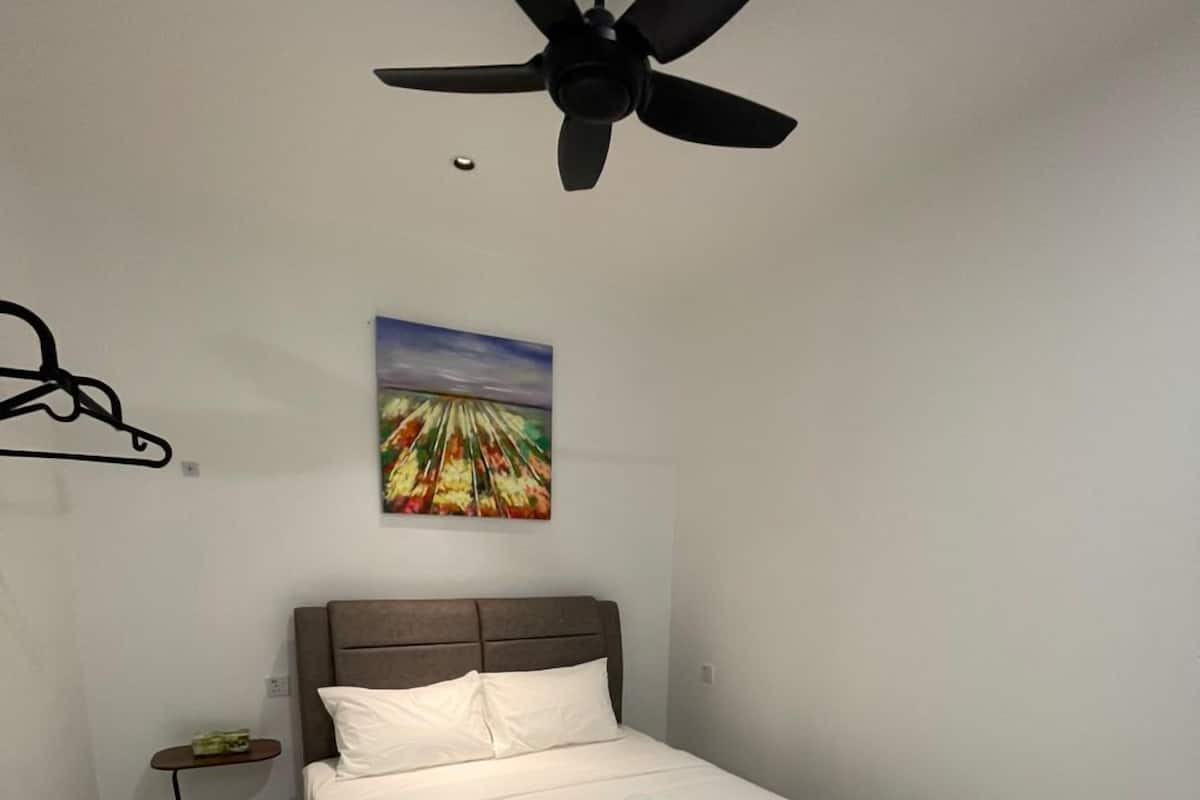 Cama bem arrumada com roupa de cama branca e dois toalhas brancas sobre ela.
