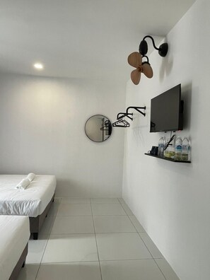 A modern hotel room with a bed, a TV, a mirror, and a shelf with toiletries. - TDOZE Hotel (Brinchang)