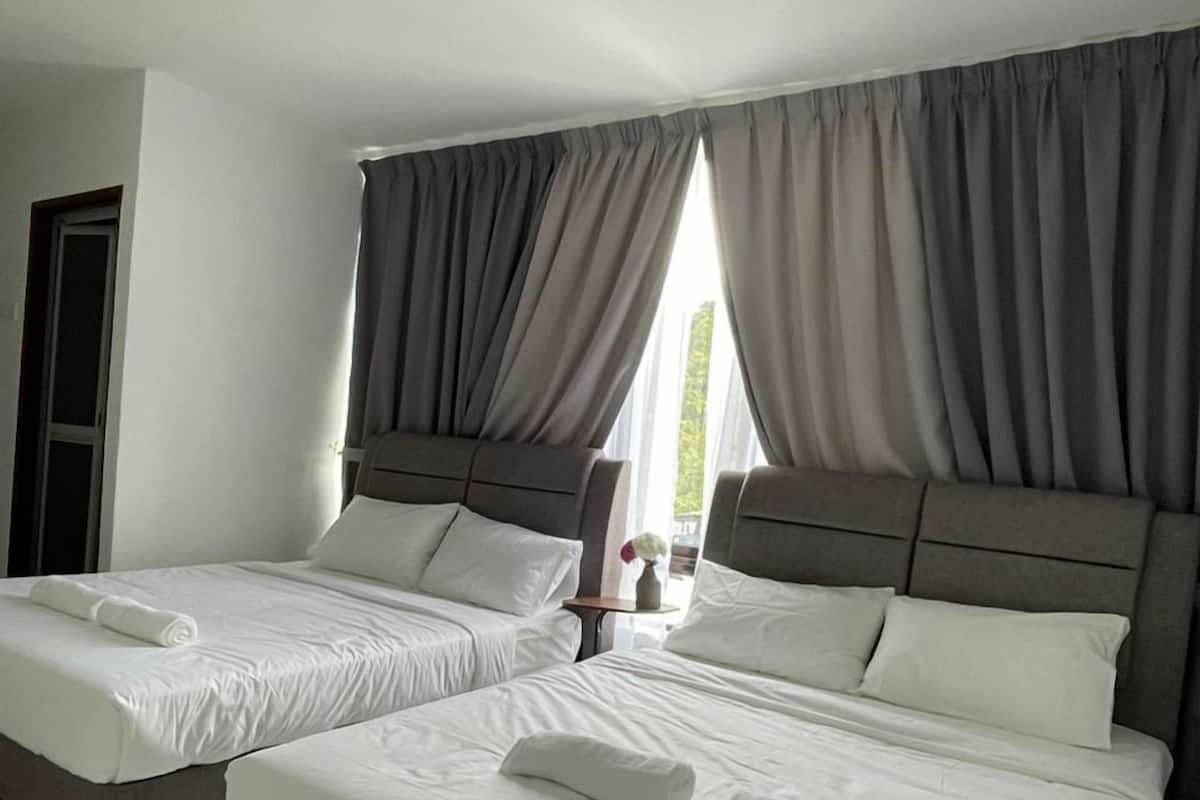 Quarto de hotel com duas camas, cortinas cinzentas, roupa de cama branca e chão de azulejos.