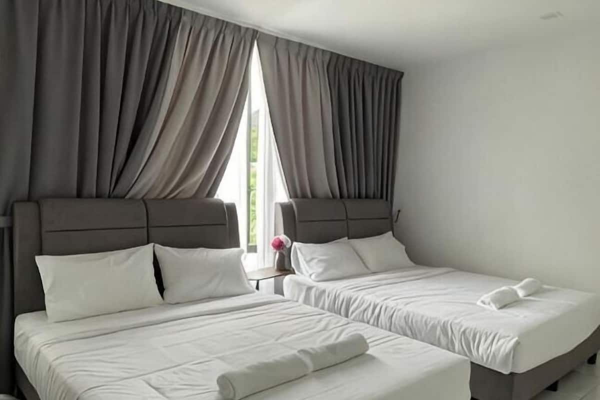 Quarto de hotel com duas camas, cortinas cinzas e uma janela.
