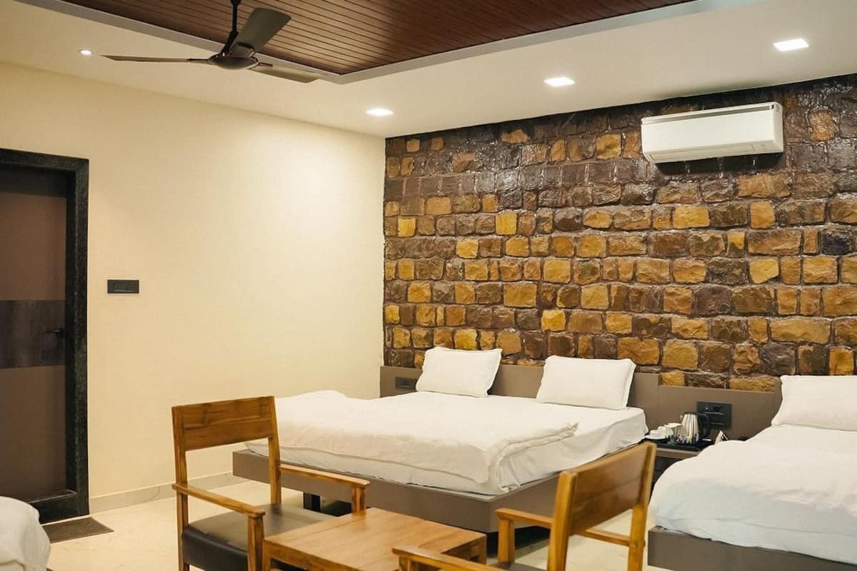 A hotel room with a stone wall, a ceiling fan, and a bed with white bedding.