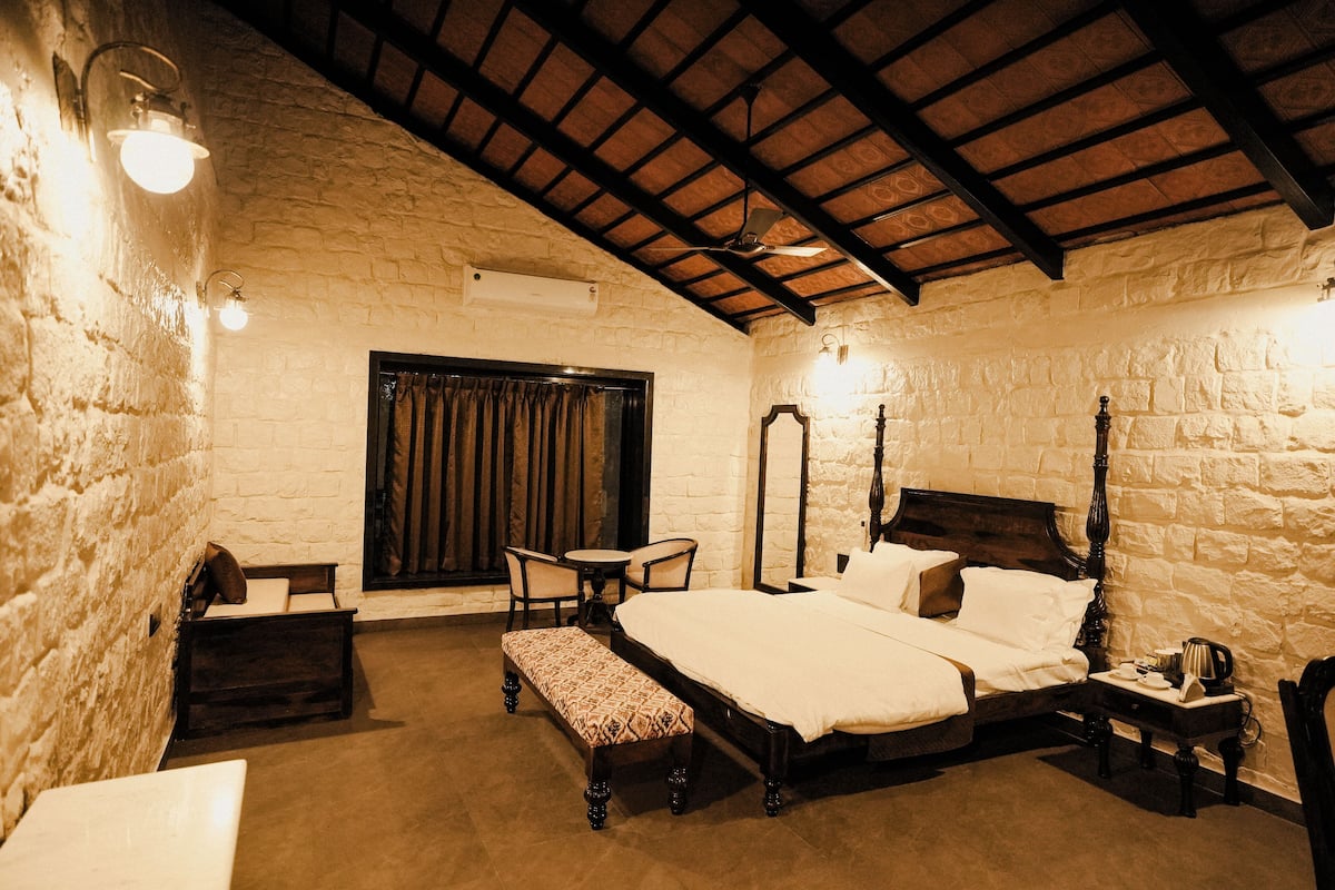 A bedroom with a four-poster bed, a bench, a small table, and a chair.