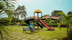 Un parque infantil con tobogán, columpios y un banco.