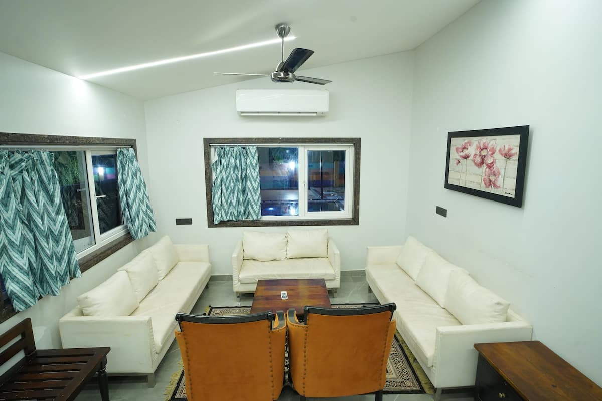A living room with two white sofas, a wooden coffee table, and a ceiling fan.