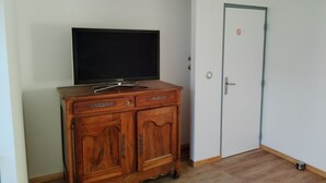 Ein Zimmer mit einem Holzschrank, einem Flachbildfernseher und einer weißen Tür mit einem roten Kreis.