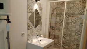 Ein Badezimmer mit Waschbecken, Spiegel, Dusche und Fliesen mit Muster.