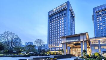 A modern hotel with a prominent entrance and a well-maintained outdoor area with a water feature and landscaped gardens.