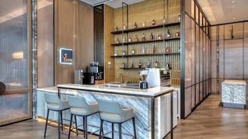 A modern bar area with a marble countertop, bar stools, and a wall of liquor bottles.