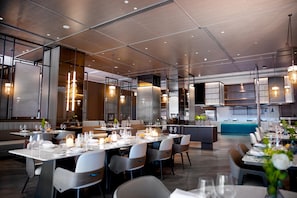 Un restaurante moderno con varias zonas de comedor, incluyendo un bar y un salón privado.