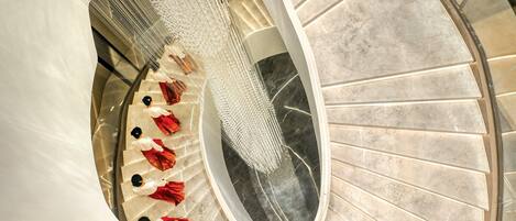 A spiral staircase with a marble floor and a glass railing.