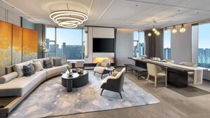 Una sala de estar moderna con un sofá curvo, una mesa de centro y un comedor con una mesa larga y sillas.