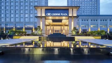 A modern hotel entrance with a reflective water feature in front.