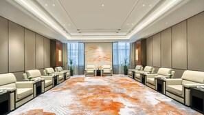 A conference room with a large, patterned carpet, leather sofas, and a modern ceiling design.