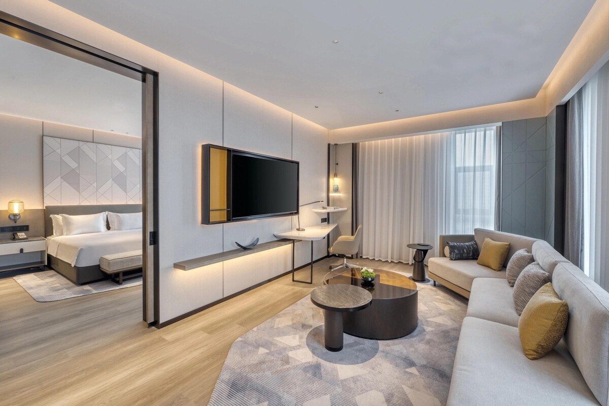 Une chambre d’hôtel moderne équipée d’un lit, d’un canapé, d’une table basse, d’une télévision et d’un bureau.
