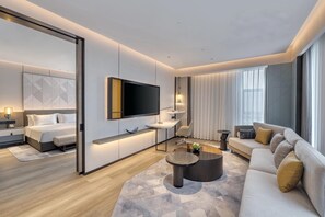 Une chambre d’hôtel moderne équipée d’un lit, d’un canapé, d’une table basse, d’une télévision et d’un bureau.