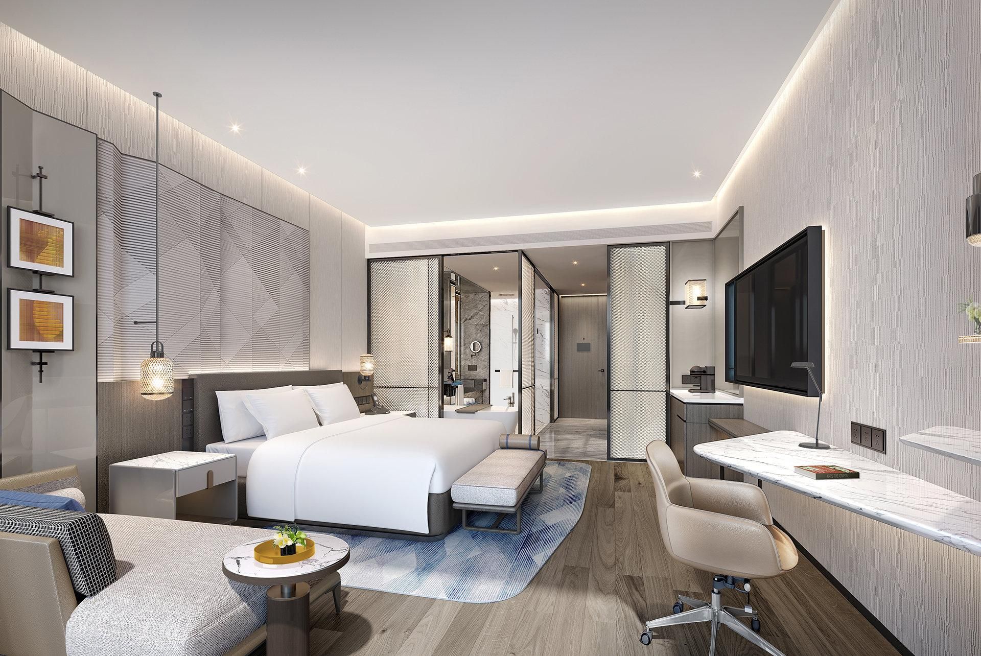A modern hotel room with a large bed, a desk, a chair, and a TV.