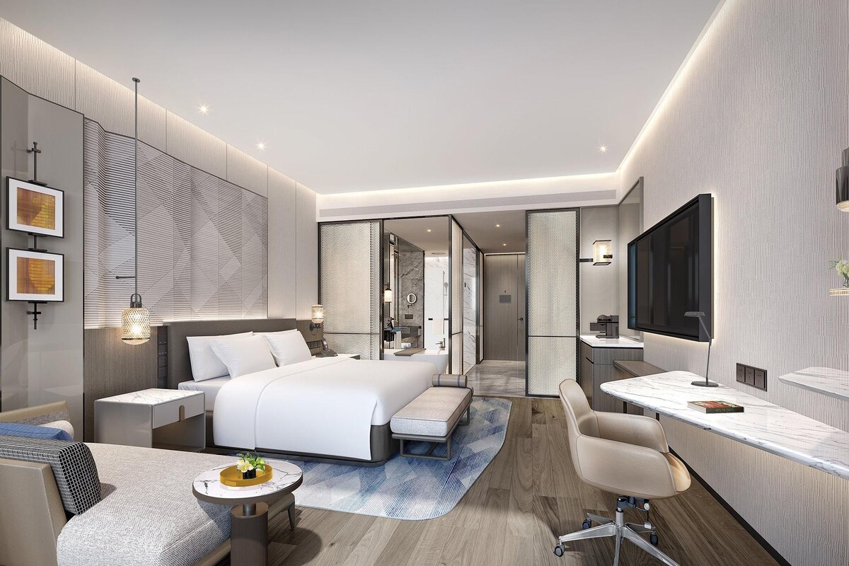 Une chambre d’hôtel moderne équipée d’un grand lit, d’un bureau, d’une chaise et d’une télévision.