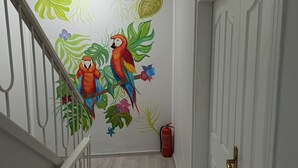 En gang med en hvid dør, en brandslukker og en trappe med gelænder.