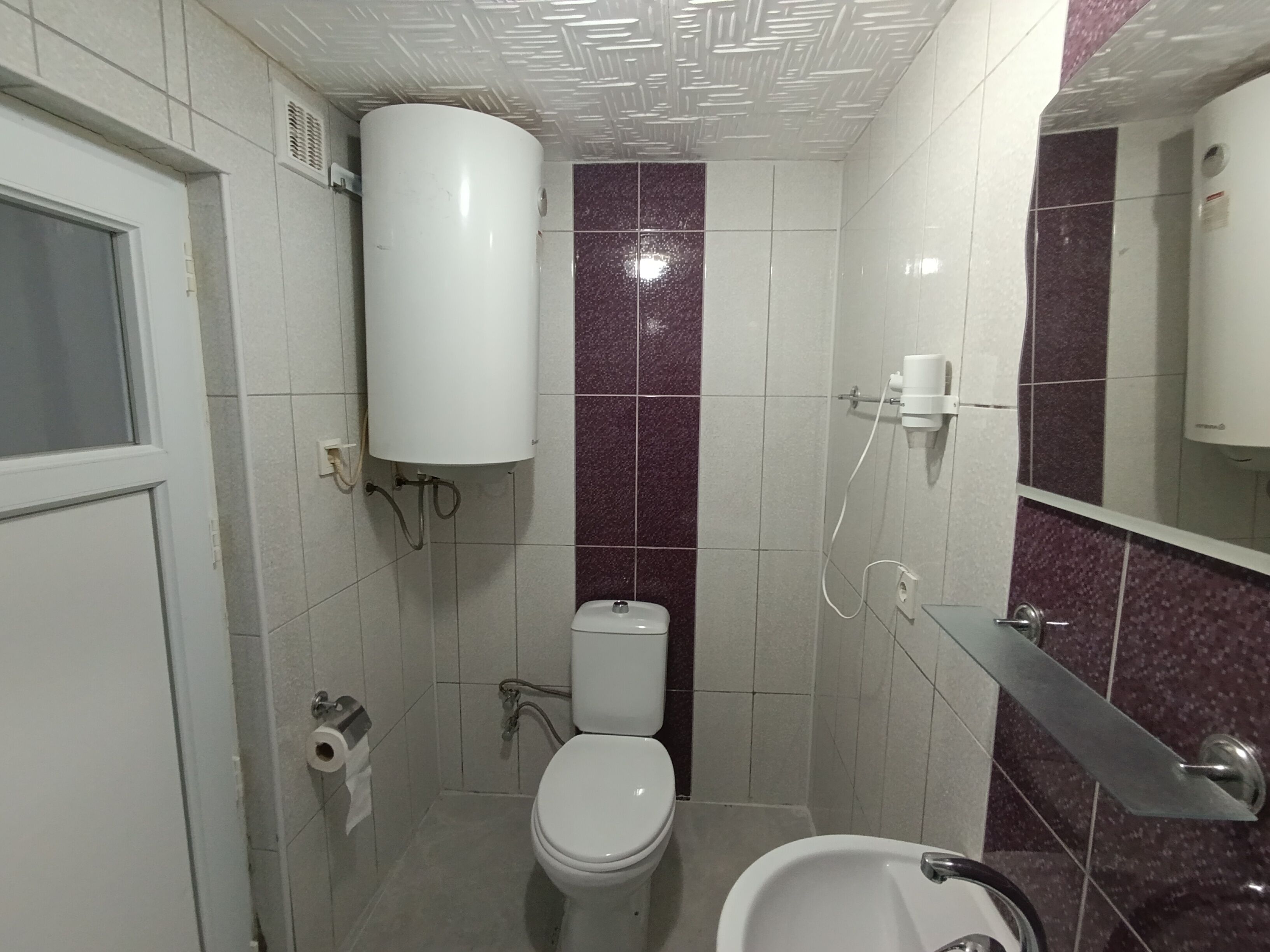 A small bathroom with a toilet, a sink, and a shower.