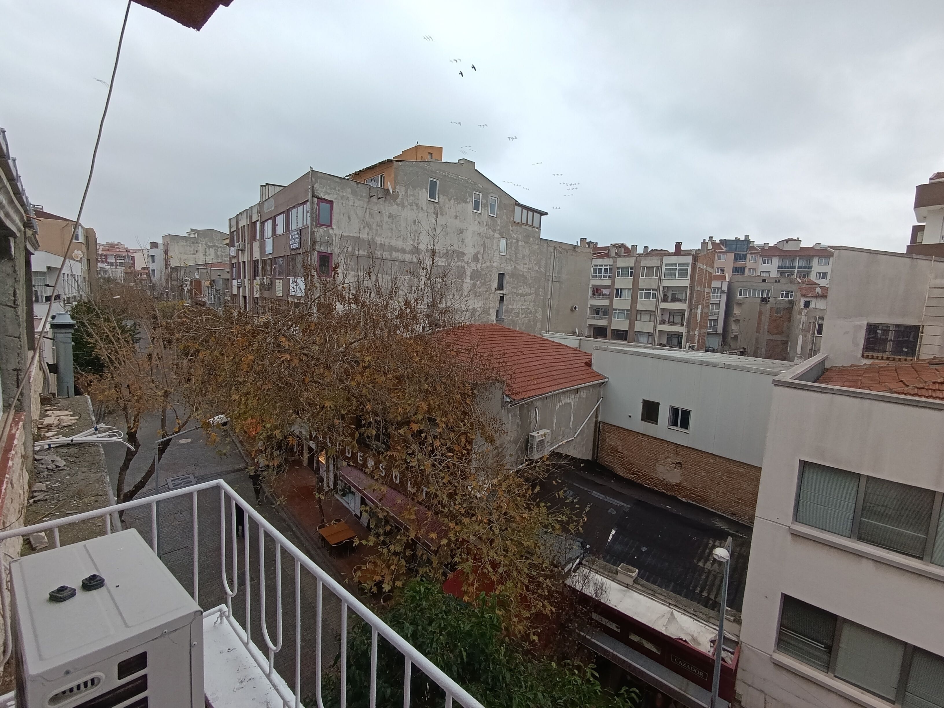 Un edificio de varios pisos con techo de tejas rojas y un balcón.