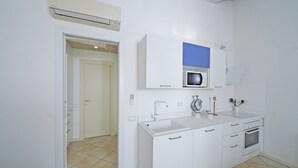 Een moderne keuken met witte kastjes, een inbouwmagnetron en een spoelbak.