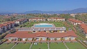 Un resort con varias edificaciones, una piscina central y montañas al fondo.