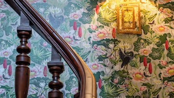 A wooden staircase with a floral wallpaper background.