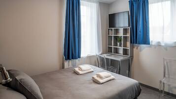 A modern hotel room with a large bed, a desk, and a TV.