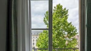 A window with a view of a tree and buildings. - SmartAppart Caen République (Caen)