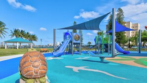 Une aire de jeux avec des toboggans et une sculpture de tortue.