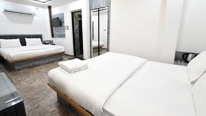 A modern hotel room with two beds, a flat-screen TV, and a coffee machine. - Namah Inn (Varanasi)