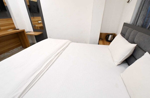 A hotel room with a bed, a bedside table, and a nightstand.