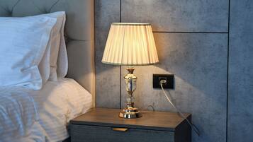 A neatly made bed with white linens, a bedside table with a lamp, and a wall with a textured finish.