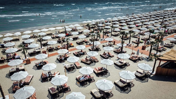 A beach with numerous sun loungers and umbrellas, arranged in rows. - Building Stefan Resort Nord (Navodari)