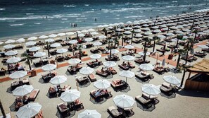 A beach with numerous sun loungers and umbrellas, arranged in rows. - Building Stefan Resort Nord (Navodari)