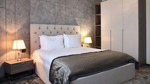 A modern bedroom with a tufted headboard, a large bed, bedside lamps, and a wardrobe. - Building Stefan Resort Nord (Navodari)