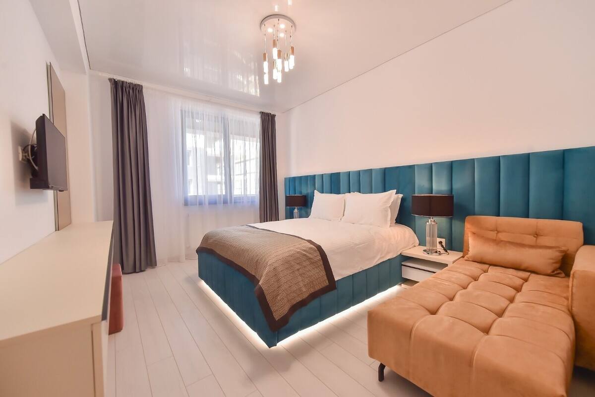 A modern hotel room with a bed, bedside table, lamp, and a television.
