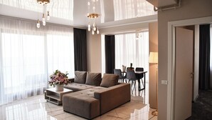 A modern living room with a sectional sofa, a dining area, and a chandelier. - Building Stefan Resort Nord (Navodari)