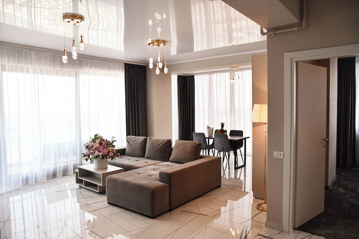 A modern living room with a sectional sofa, a dining area, and a chandelier.