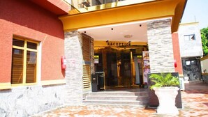 A hotel entrance with a reception desk, a glass door, and a potted plant. - Apno Hotel and Suites  (Lekki)