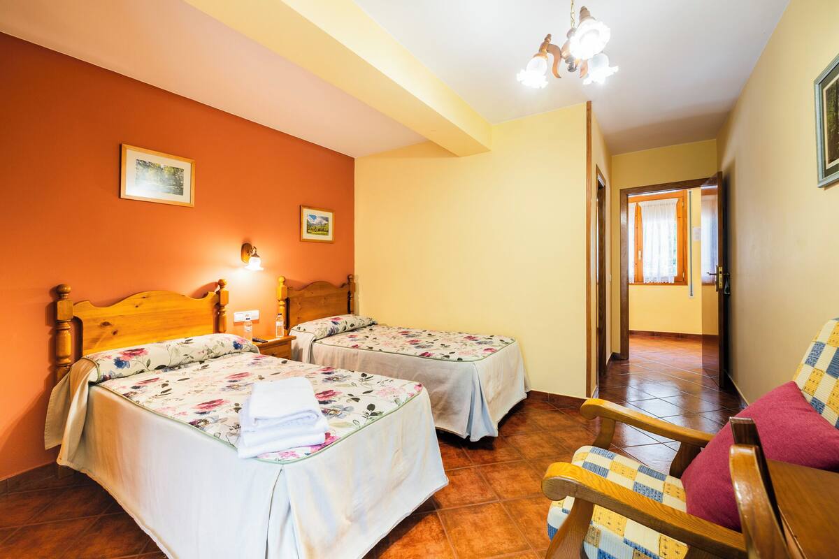 A room with two beds, a wooden chair, and a wooden table.