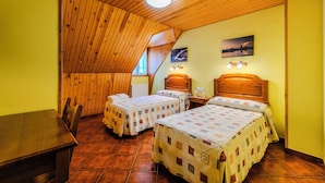 A room with two beds, wooden ceiling, and a dining table.