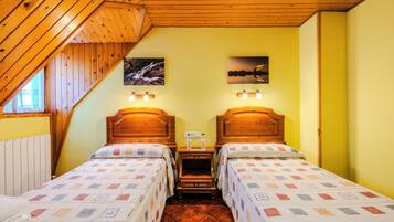 Una habitación con dos camas, cabeceros de madera y techo inclinado.