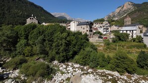 A mountain village with stone buildings, a church, and a river.